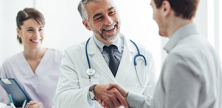 smiling doctor shaking hand of patient
